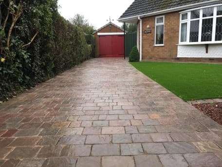 Paved driveway next to a house with a green lawn